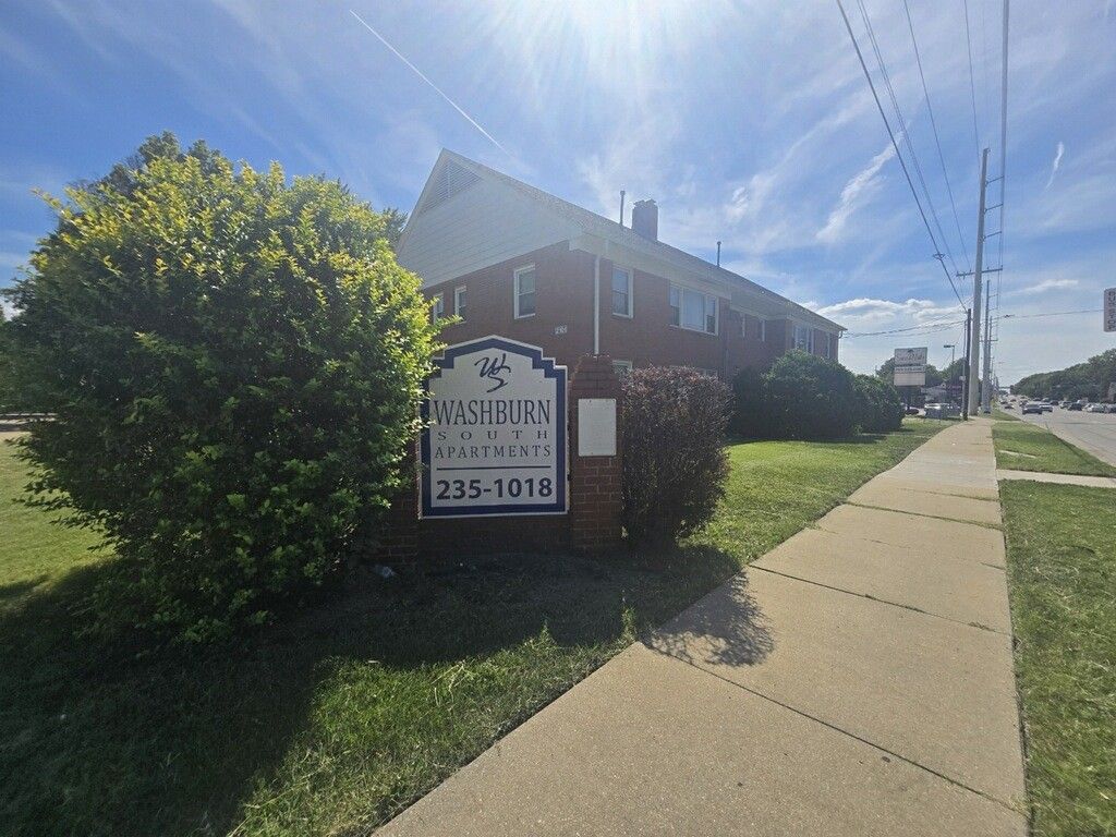 Sign for Waverly Apartments, 235-1018, next to a brick building and a sidewalk.