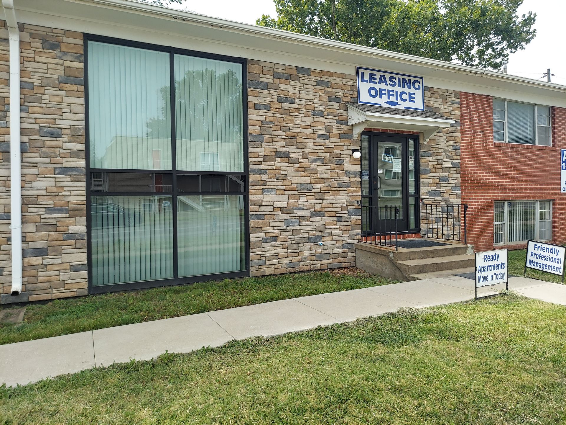 Apartment leasing office with stone facade, large windows, and