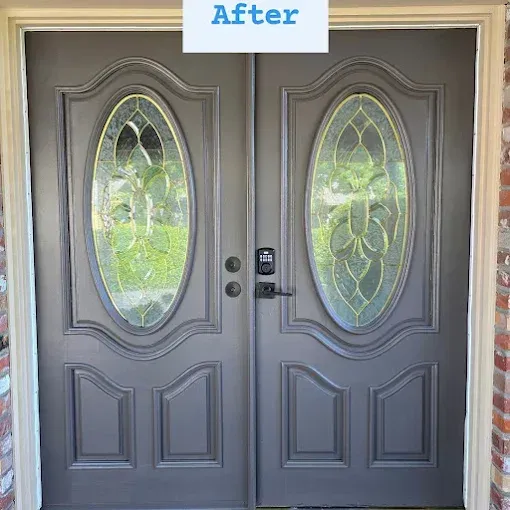 Double front doors painted dark gray with oval glass inserts and a black electronic smart lock, set in a brick frame.