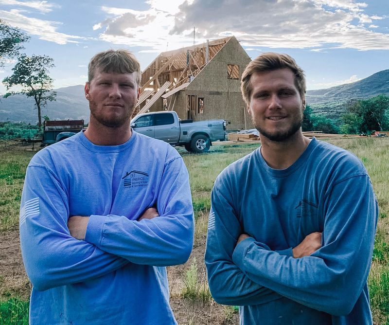 Two man standing on the ground near a house with cloudy sky in background