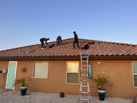 A group of men are working on the roof of a house.