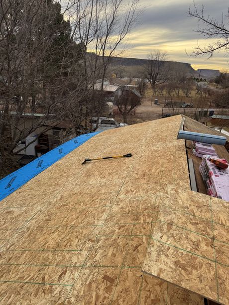A roof is being built with plywood and a hammer.