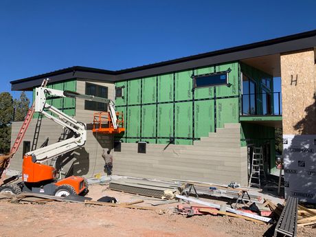 A large house is being built with a crane in front of it.