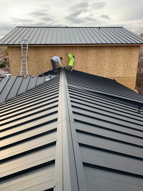 Two men are working on the roof of a house.