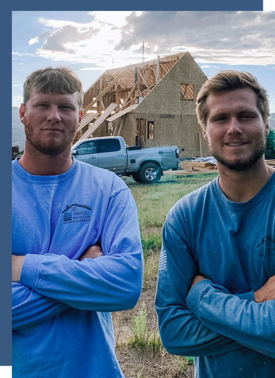 Two men are standing next to each other in front of a house under construction.