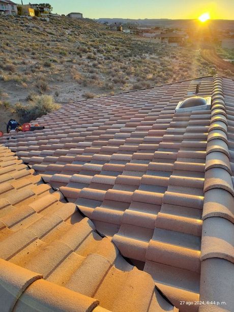 A roof with a lot of tiles on it and a sunset in the background.