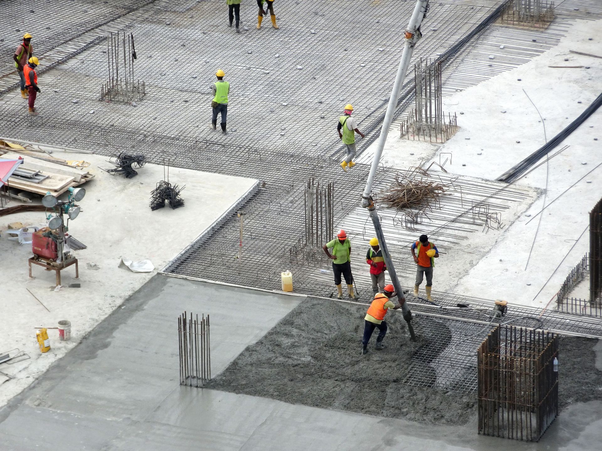 A group of construction workers are working on a concrete floor.