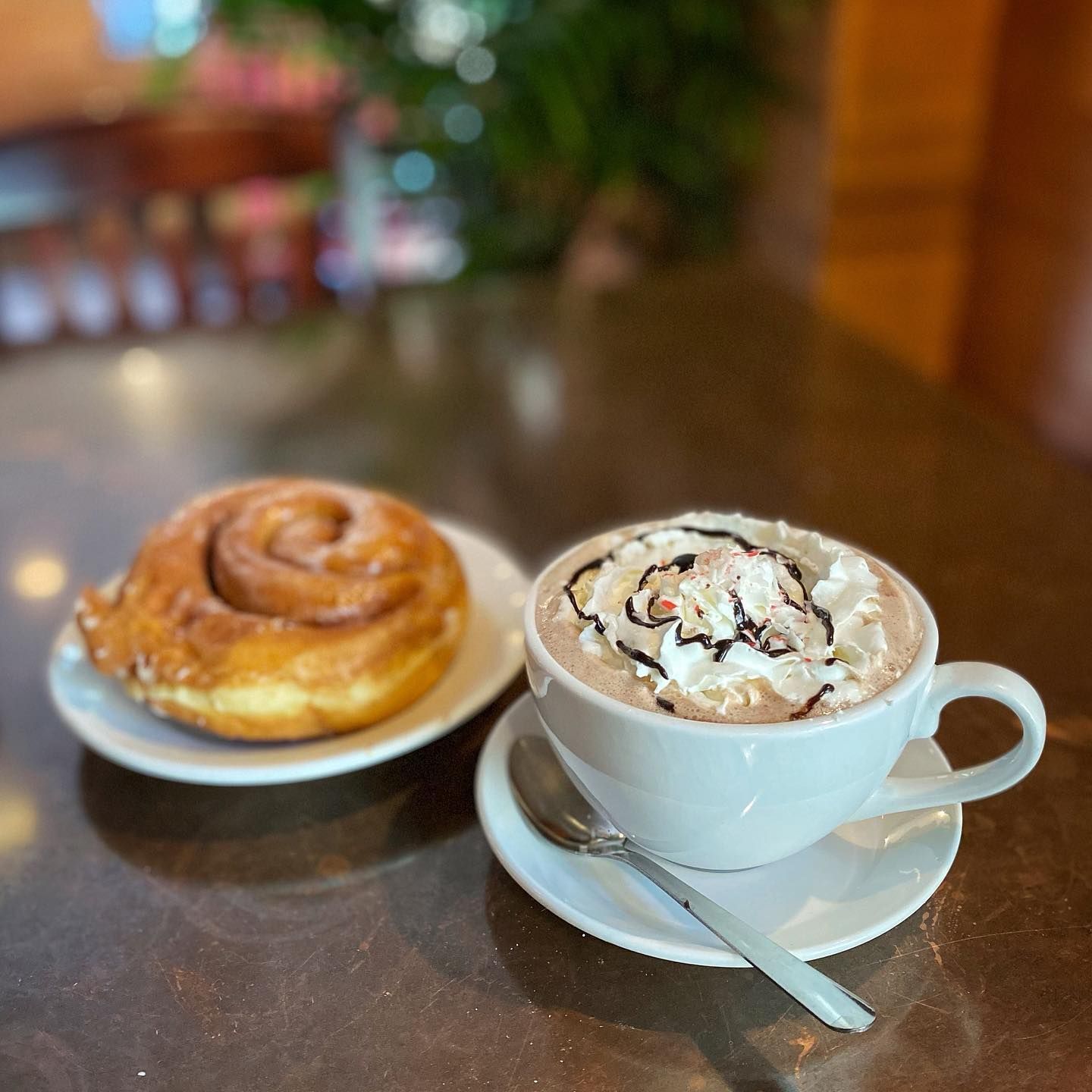 Cinnamon roll  next to a cup of hot chocolate 