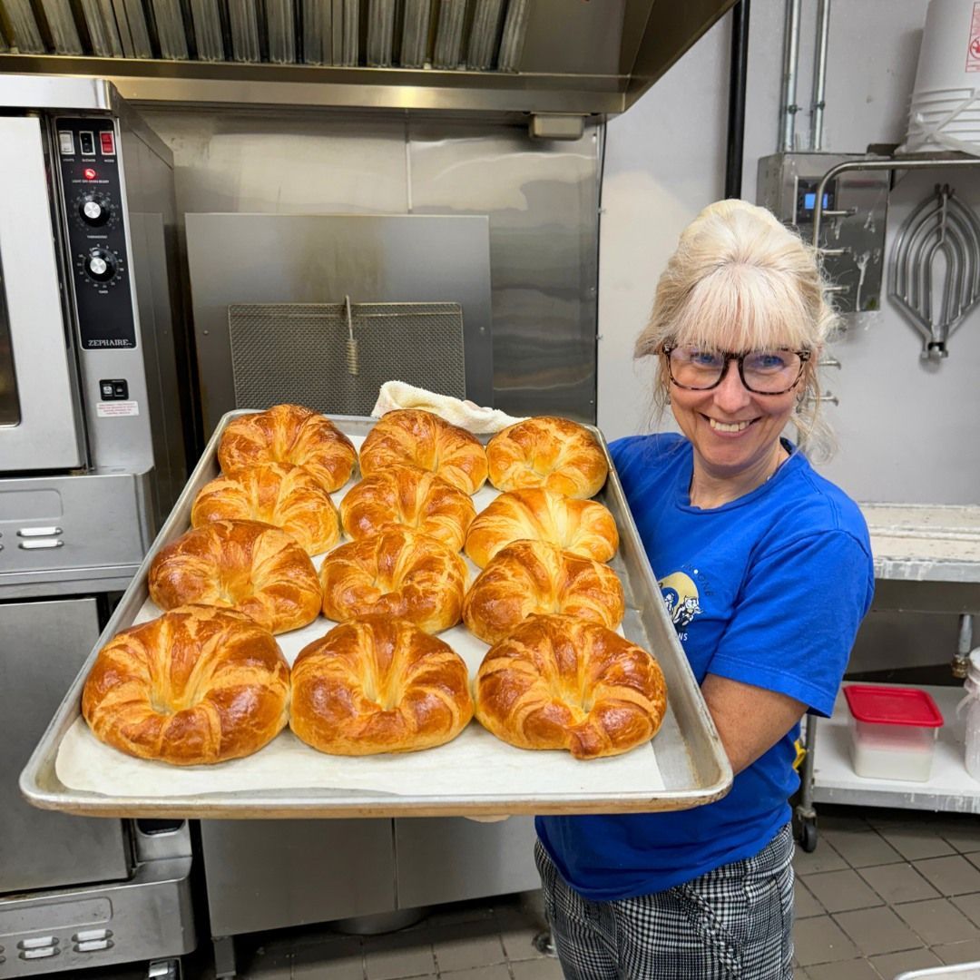 Woman holding tray of golden-brown croissants 