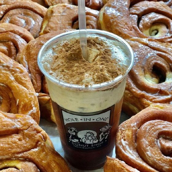 Iced coffee with cinnamon topping surrounded by cinnamon rolls.