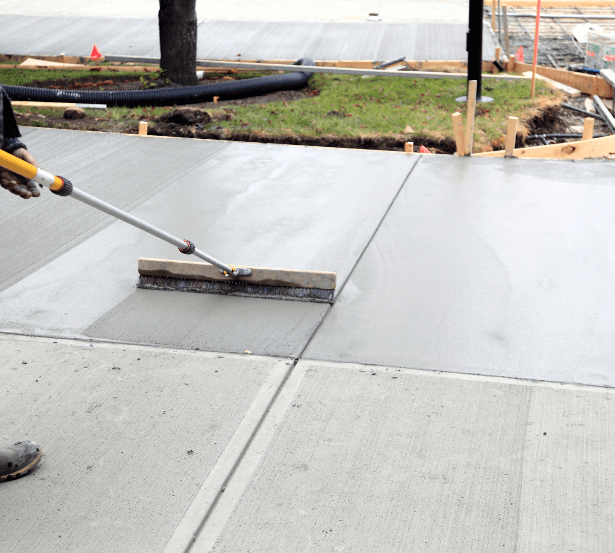 Man power washing a driveway, creating a light gray area on the dark asphalt.