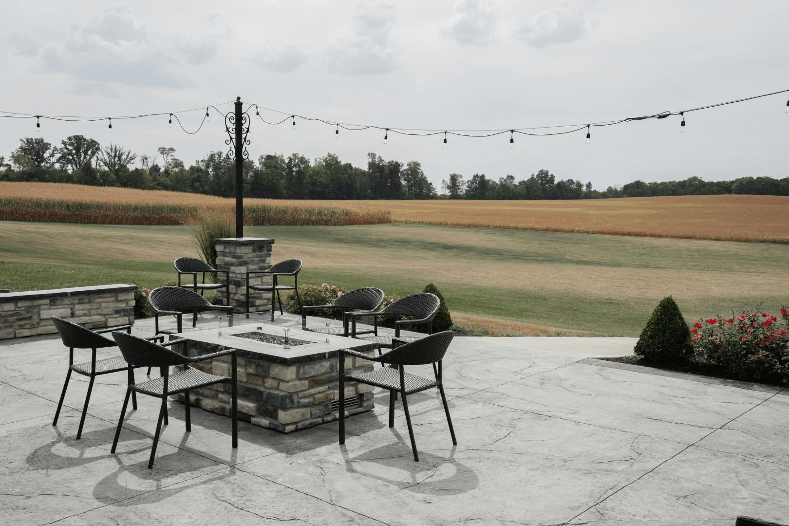A person in a reflective vest applies sealant to a paved surface. The person is holding a long-handled tool in an outdoor setting.