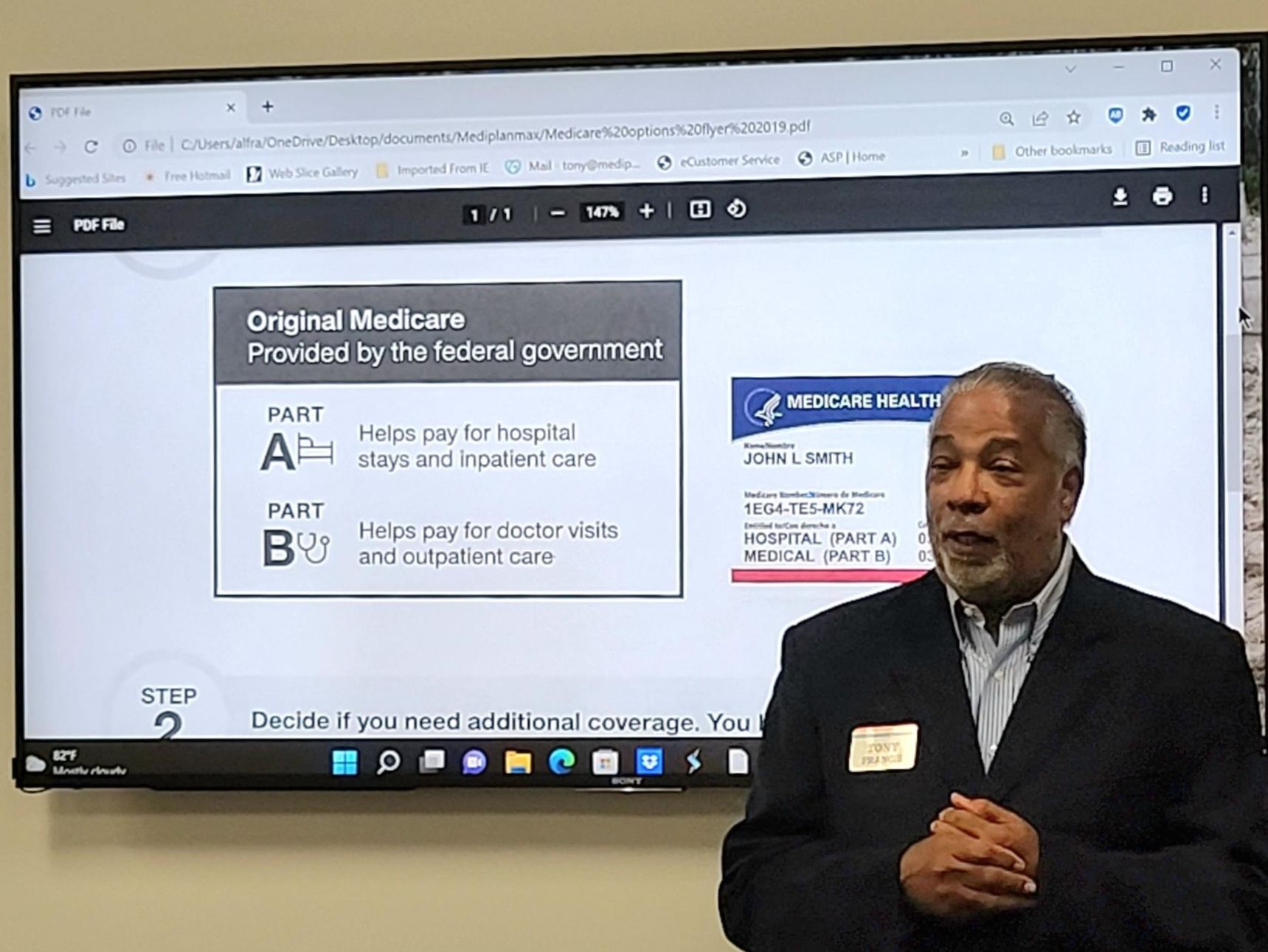 A man in a suit is standing in front of a computer screen.
