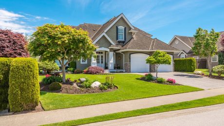 A large house with a lush green lawn and trees in front of it.