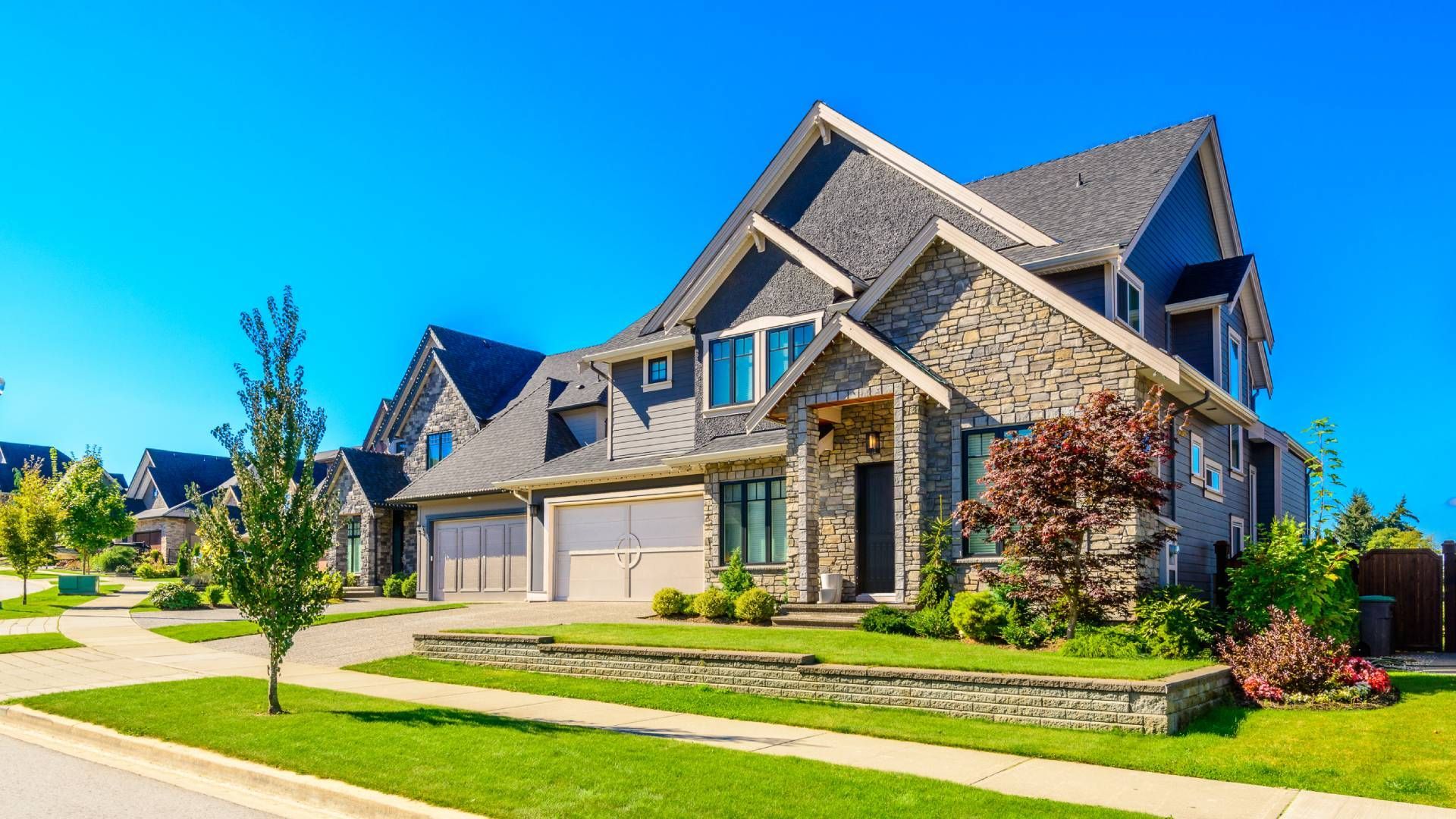 A large house is sitting on top of a lush green lawn in a residential neighborhood.