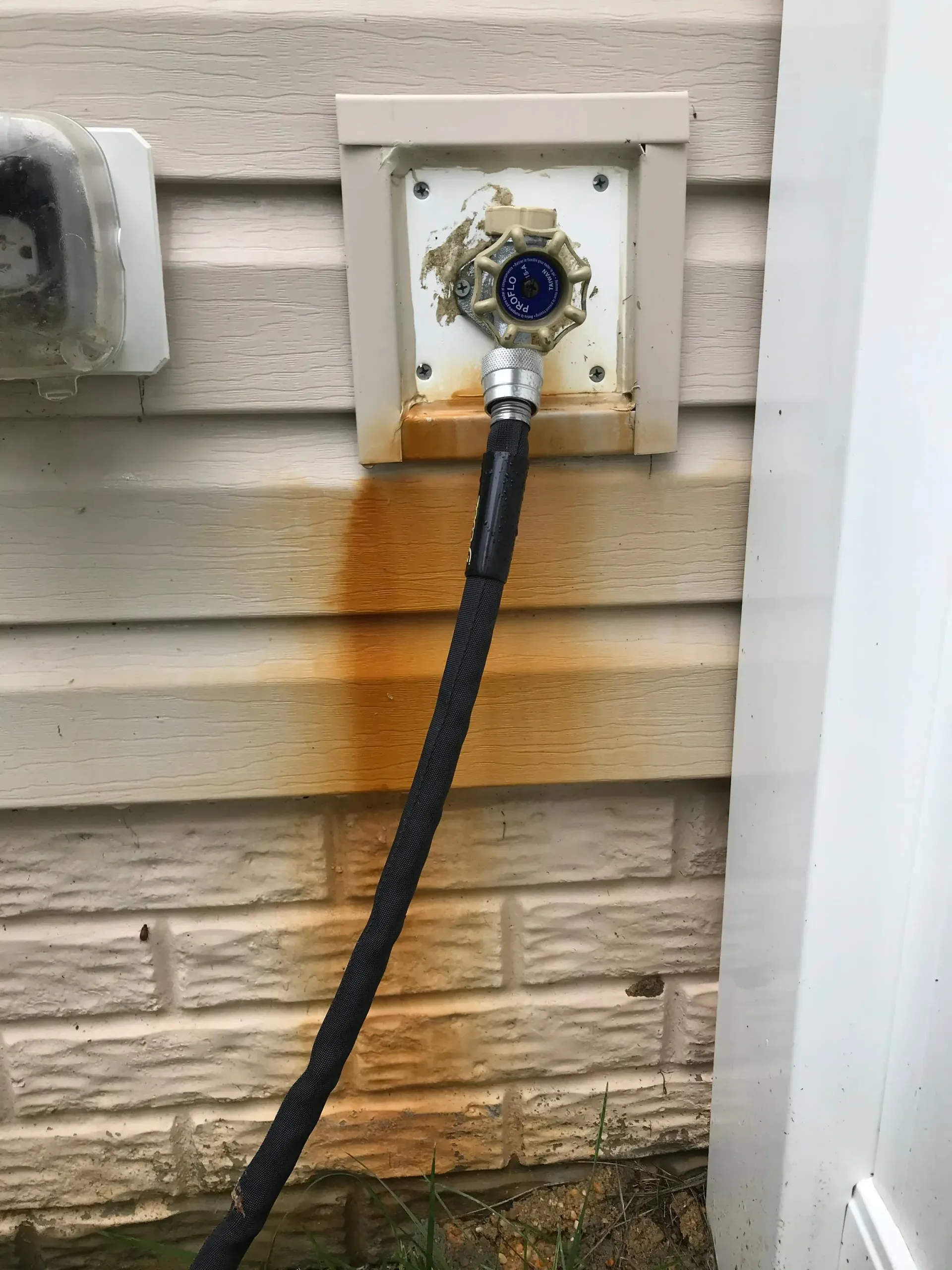 A hose is connected to a faucet on the side of a house.