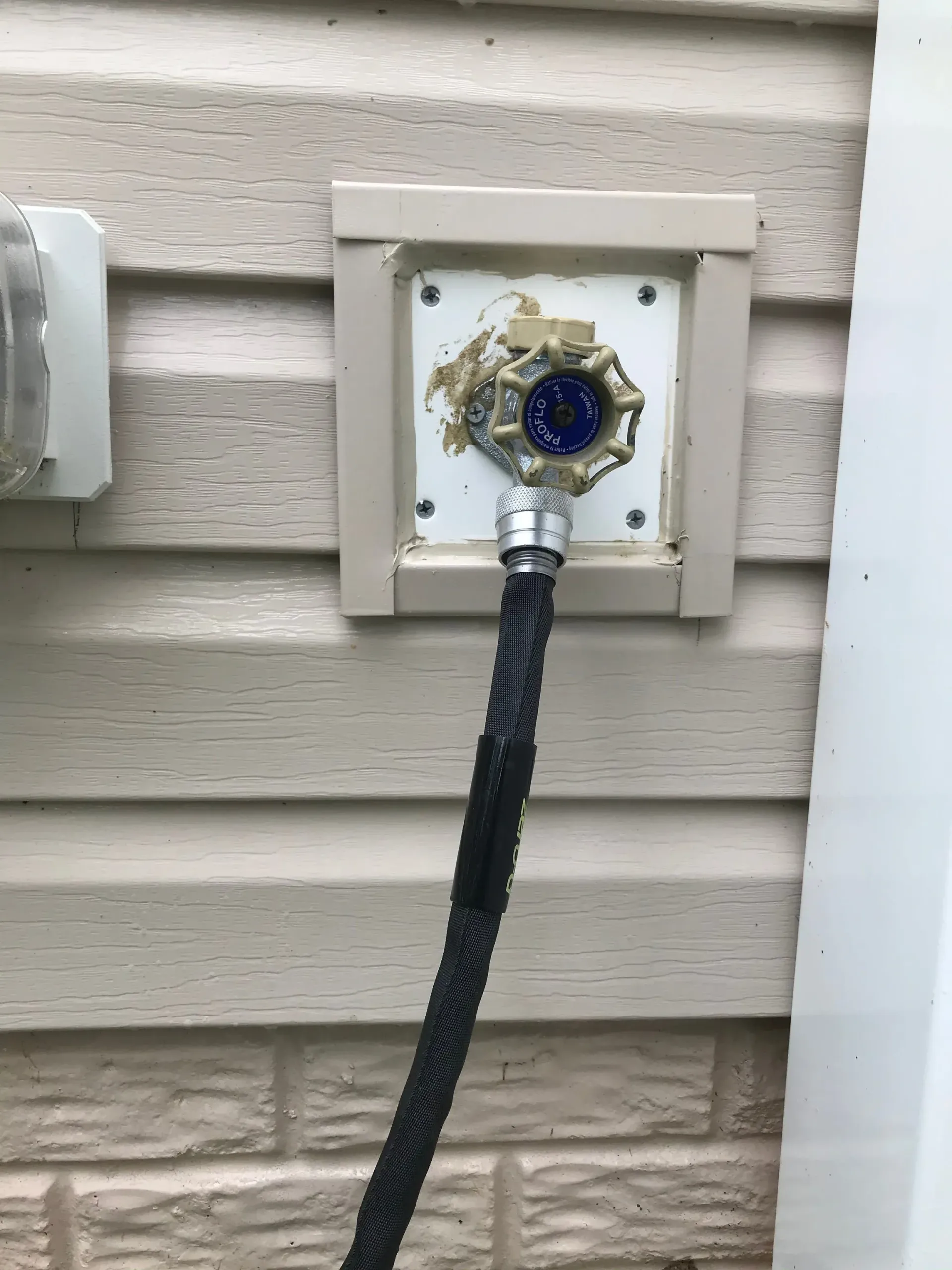 A hose is attached to a faucet on the side of a house.