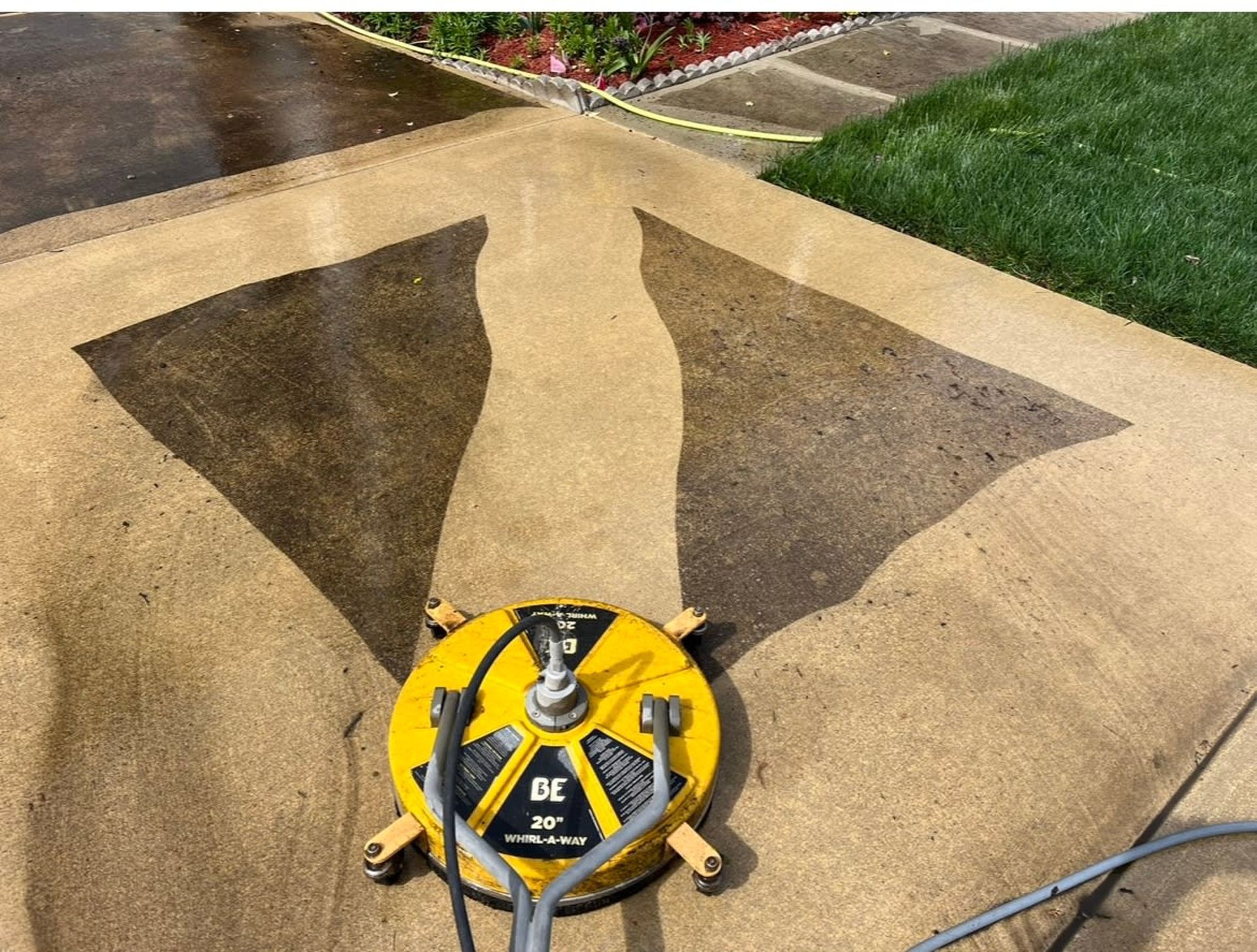 A yellow machine is being used to clean a driveway.