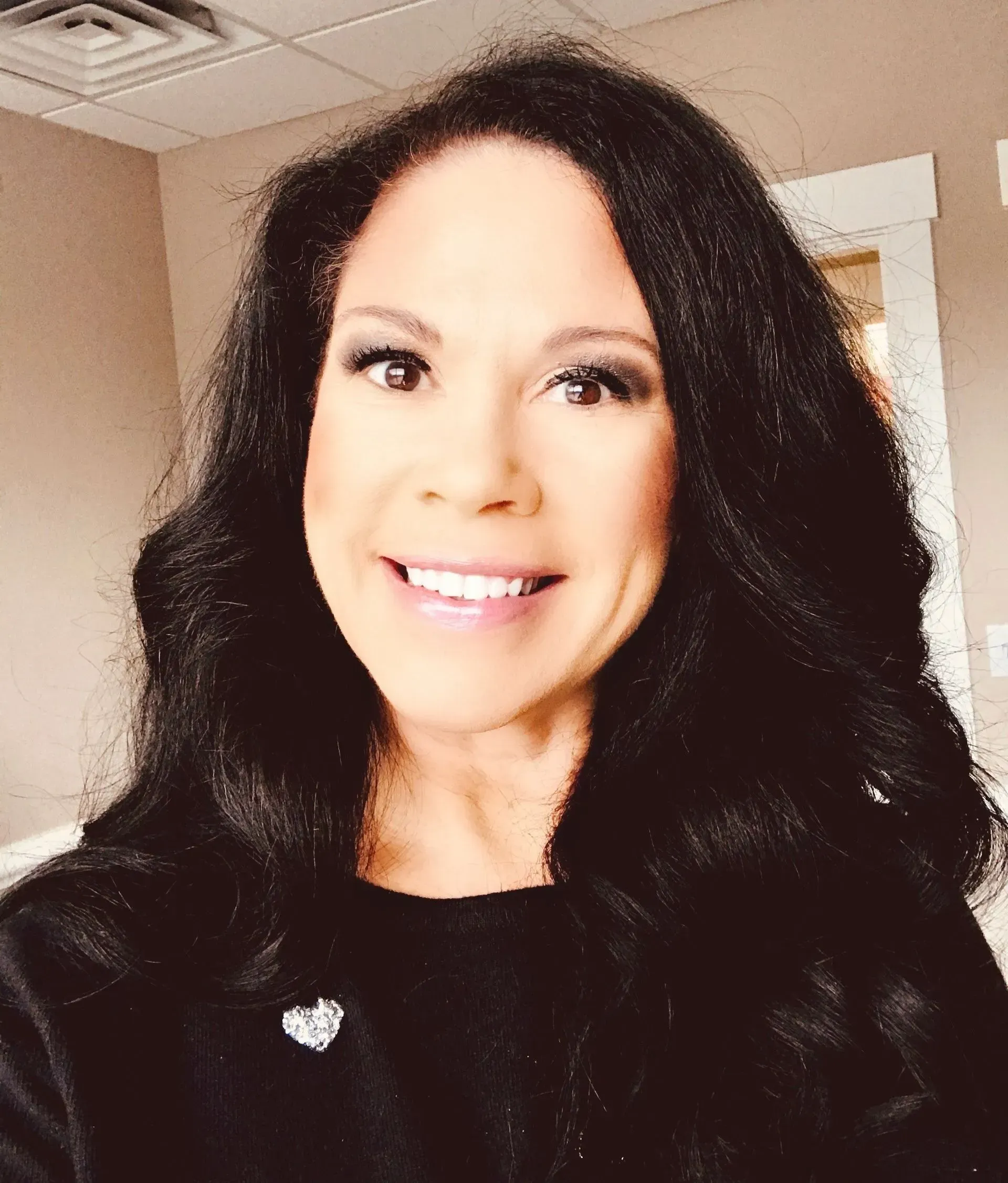 Man in navy blazer and white shirt smiles, standing in front of a world map.