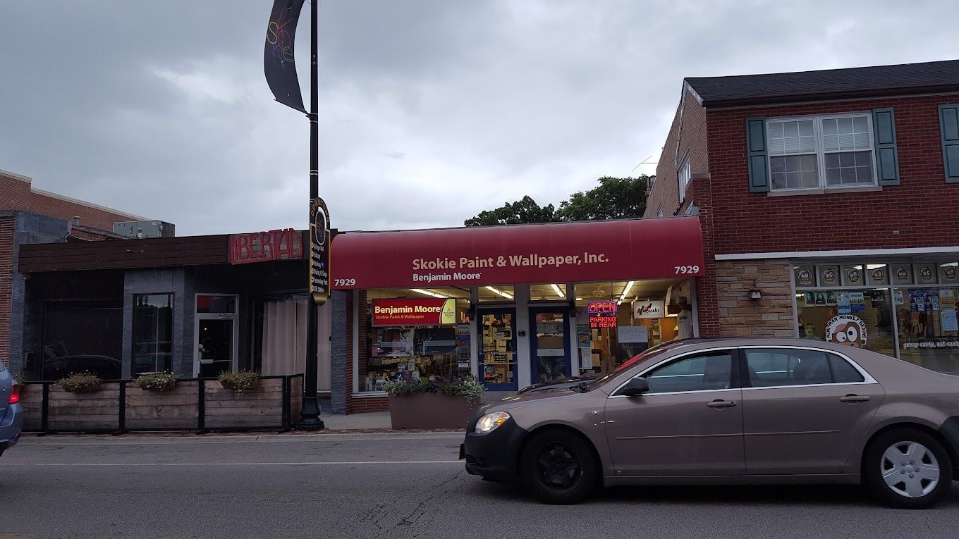 A car is parked in front of a store with a red awning.