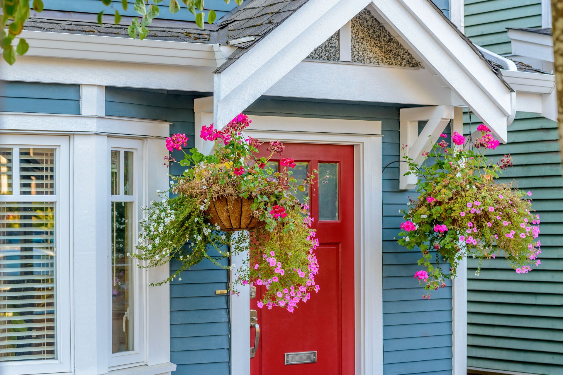A blue house with a red door and hanging baskets of flowers