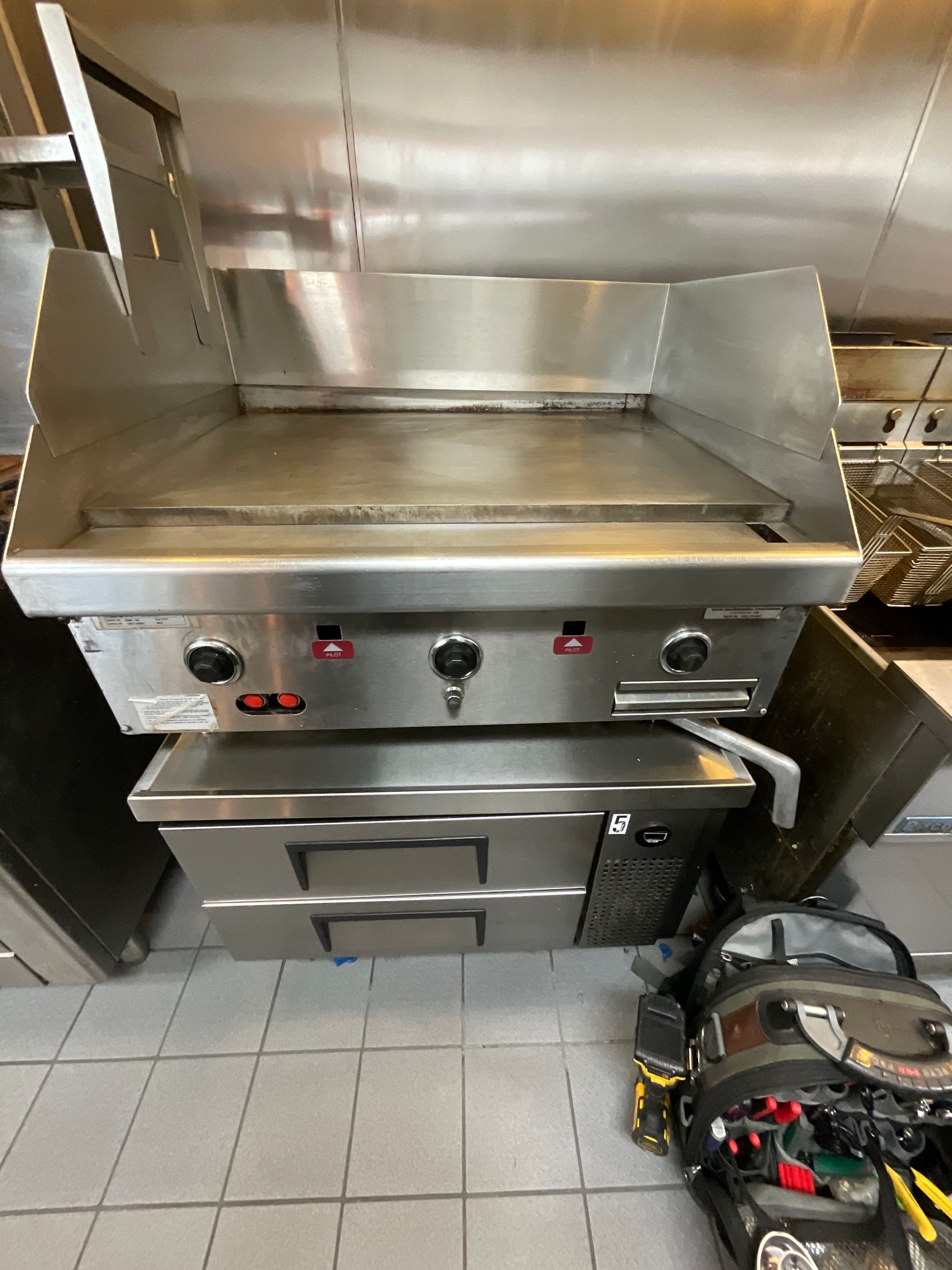 A stainless steel grill is sitting on top of a stove in a kitchen.