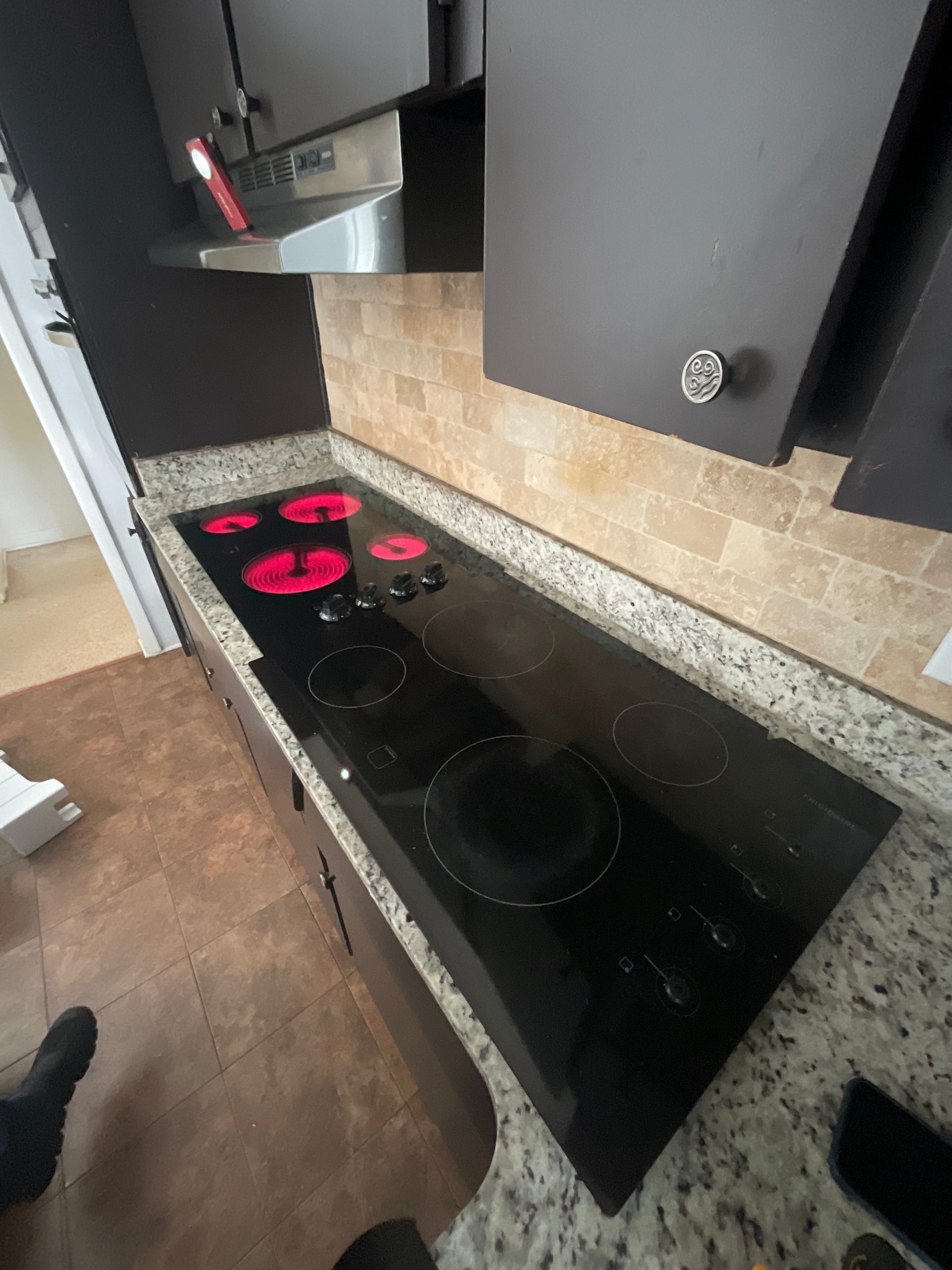 A black stove top with red burners in a kitchen