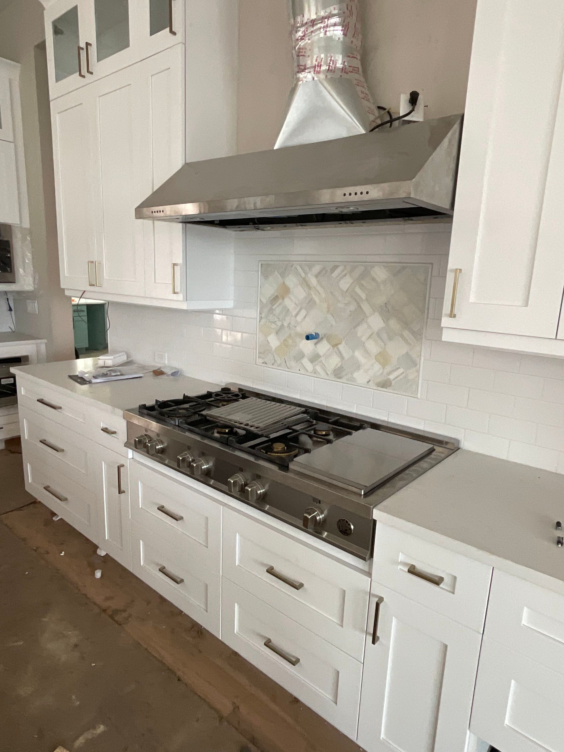 A kitchen with white cabinets and a stove top oven