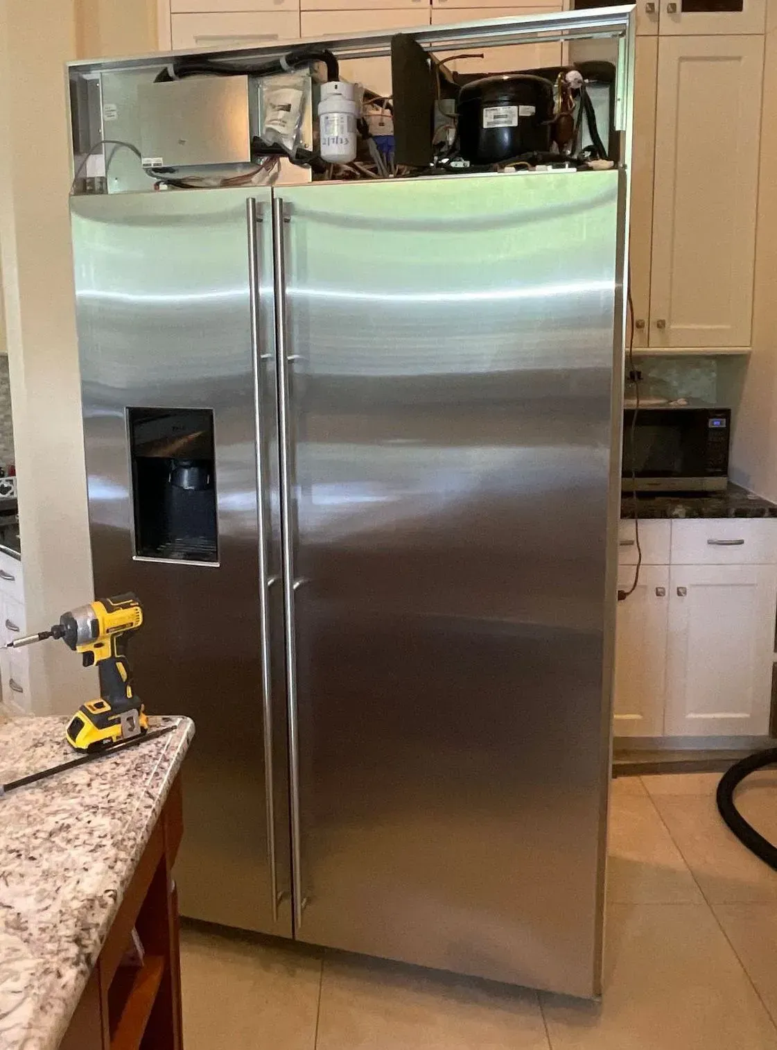 A stainless steel refrigerator is being installed in a kitchen.