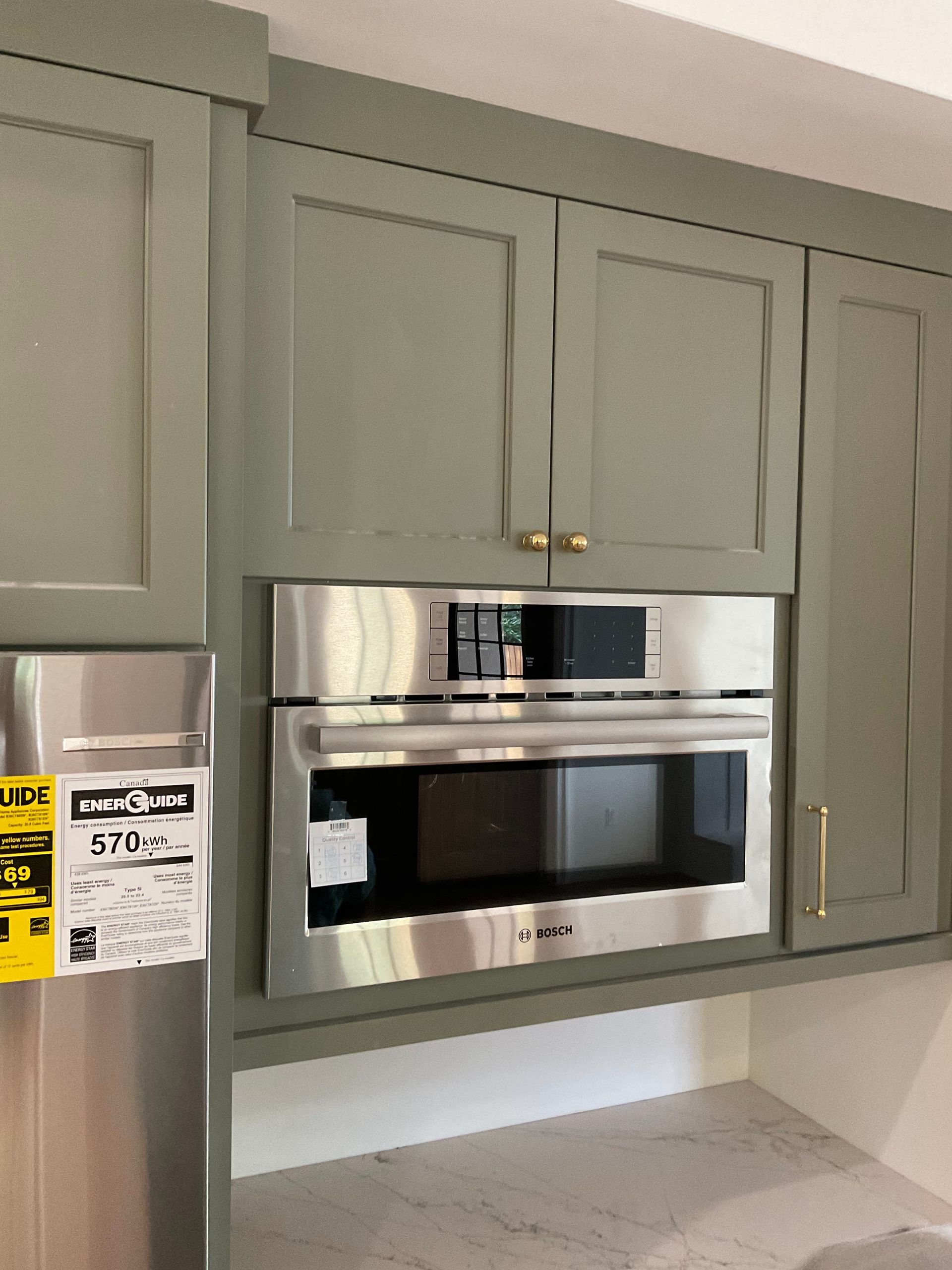 A kitchen with green cabinets and a stainless steel microwave oven