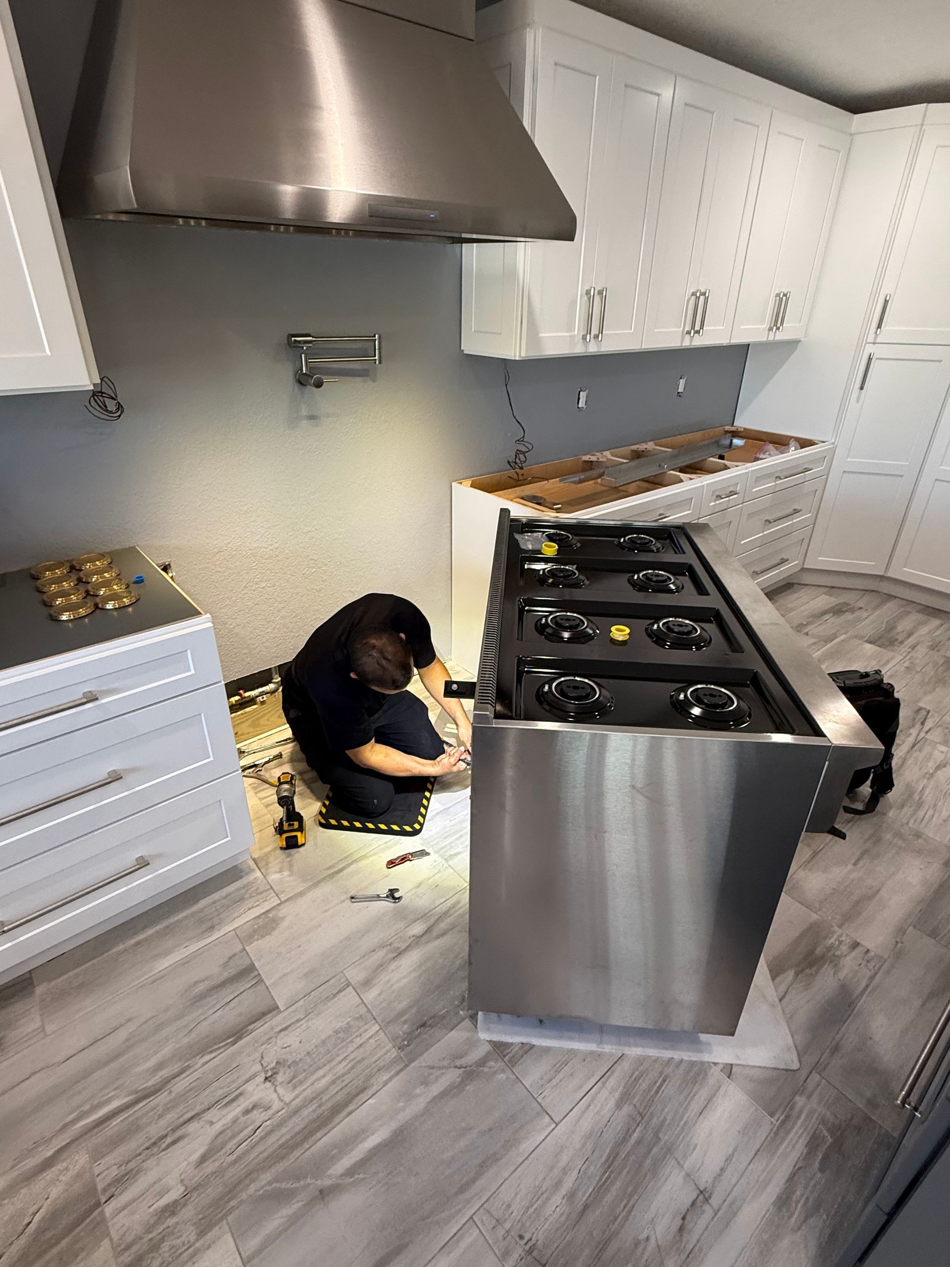 A man is working on a stove in a kitchen.
