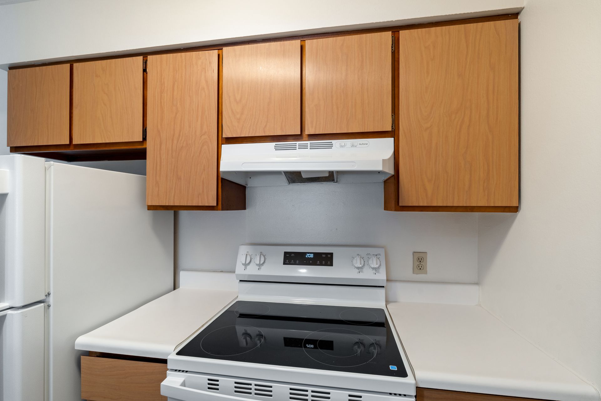 Photo of a stove in a kitchen with the refrigerator closeby