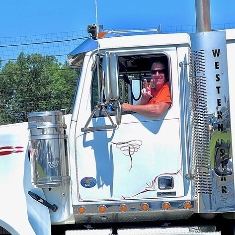 A man is standing next to a tow truck that is towing a car
