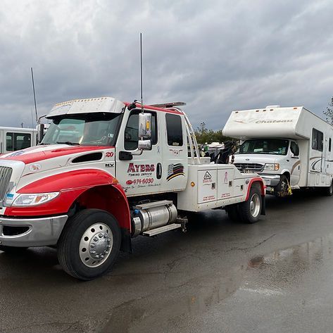 A red and white tow truck is towing a trailer.