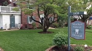 A dentist wearing blue gloves examines a patient's teeth using a dental mirror and a handpiece. A dentist wearing blue gloves examines a patient's teeth using a dental mirror and a handpiece.