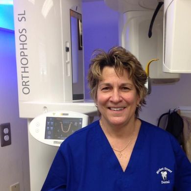 A patient holds a mirror to check their smile while a dentist in blue gloves adjusts their cheeks in a clinical office. A patient holds a mirror to check their smile while a dentist in blue gloves adjusts their cheeks in a clinical office.