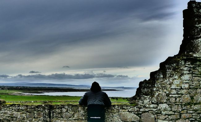 A person standing on a stone wall overlooking Easkey left