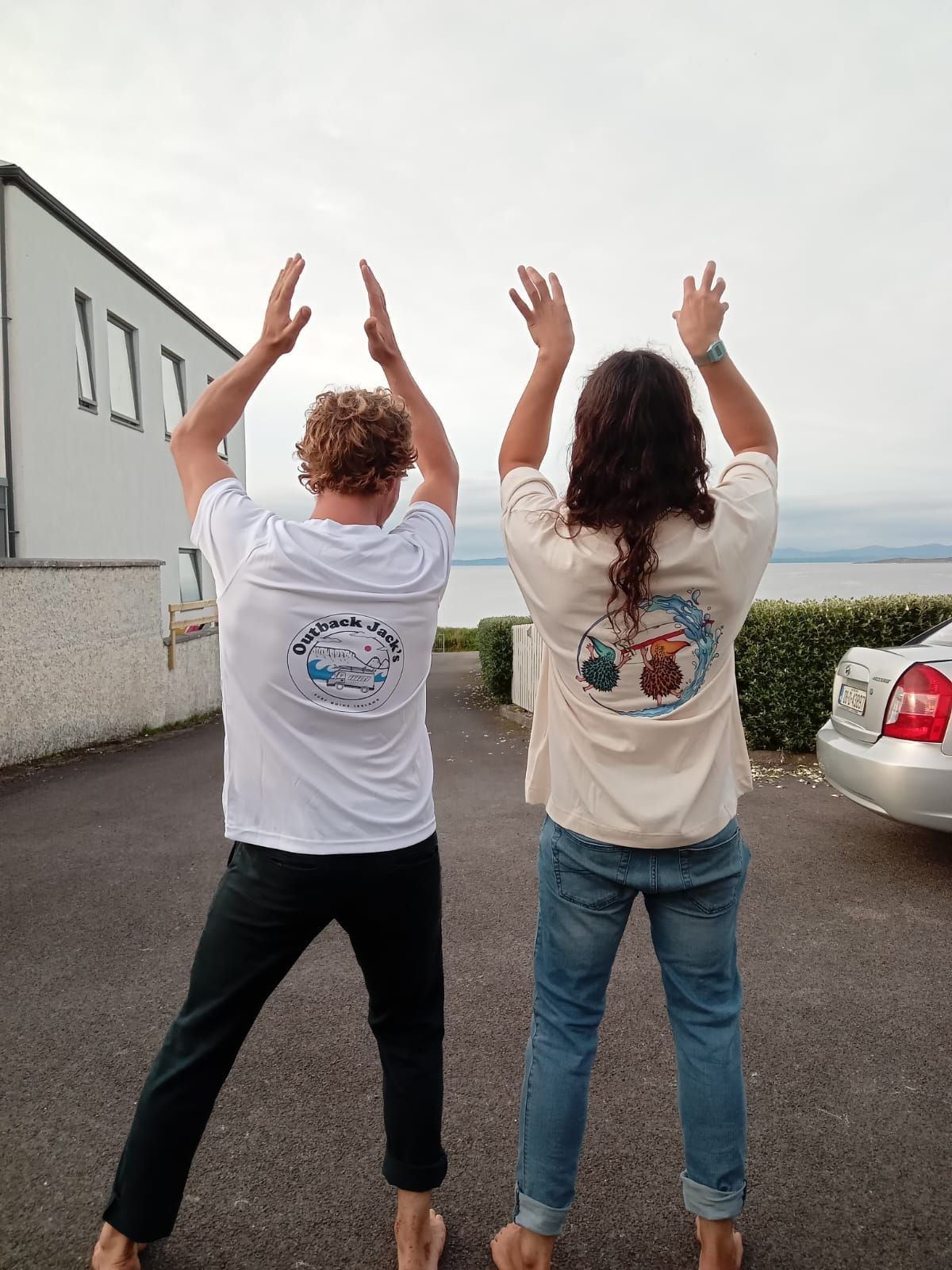 two friends are standing next to each other with their arms in the air.