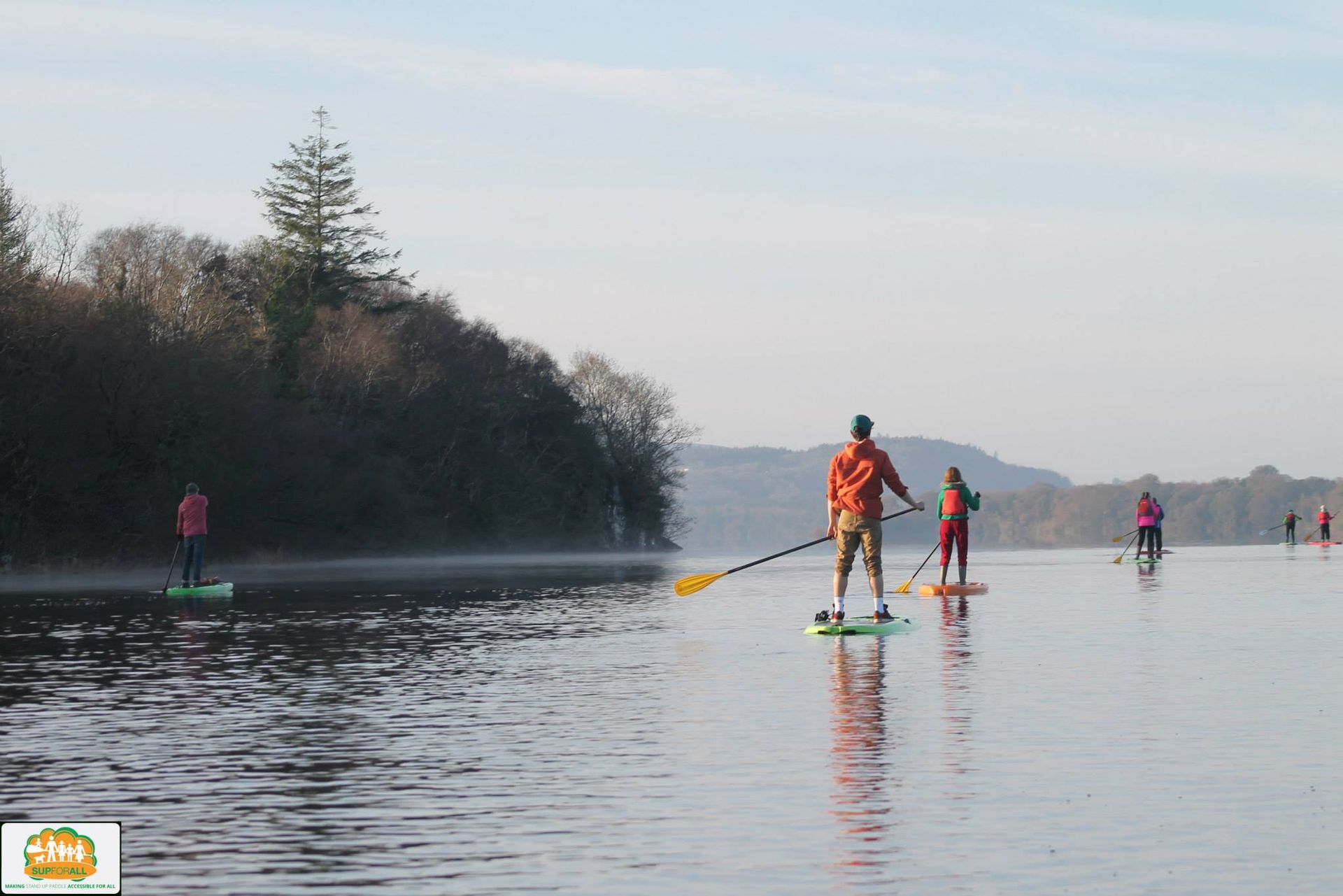A group of people are paddle boarding on a lake