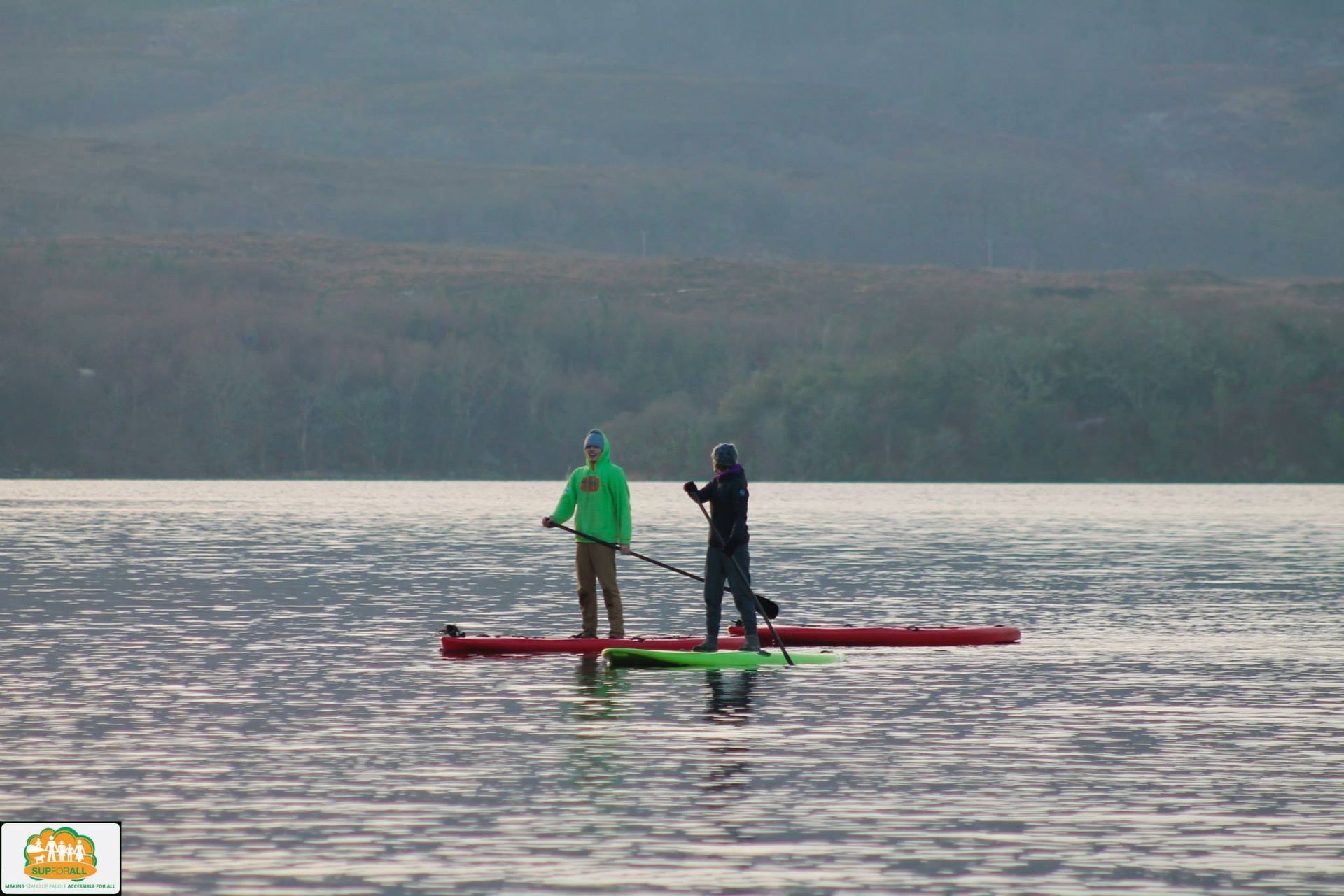 Two people are standing on a paddle board in the water.