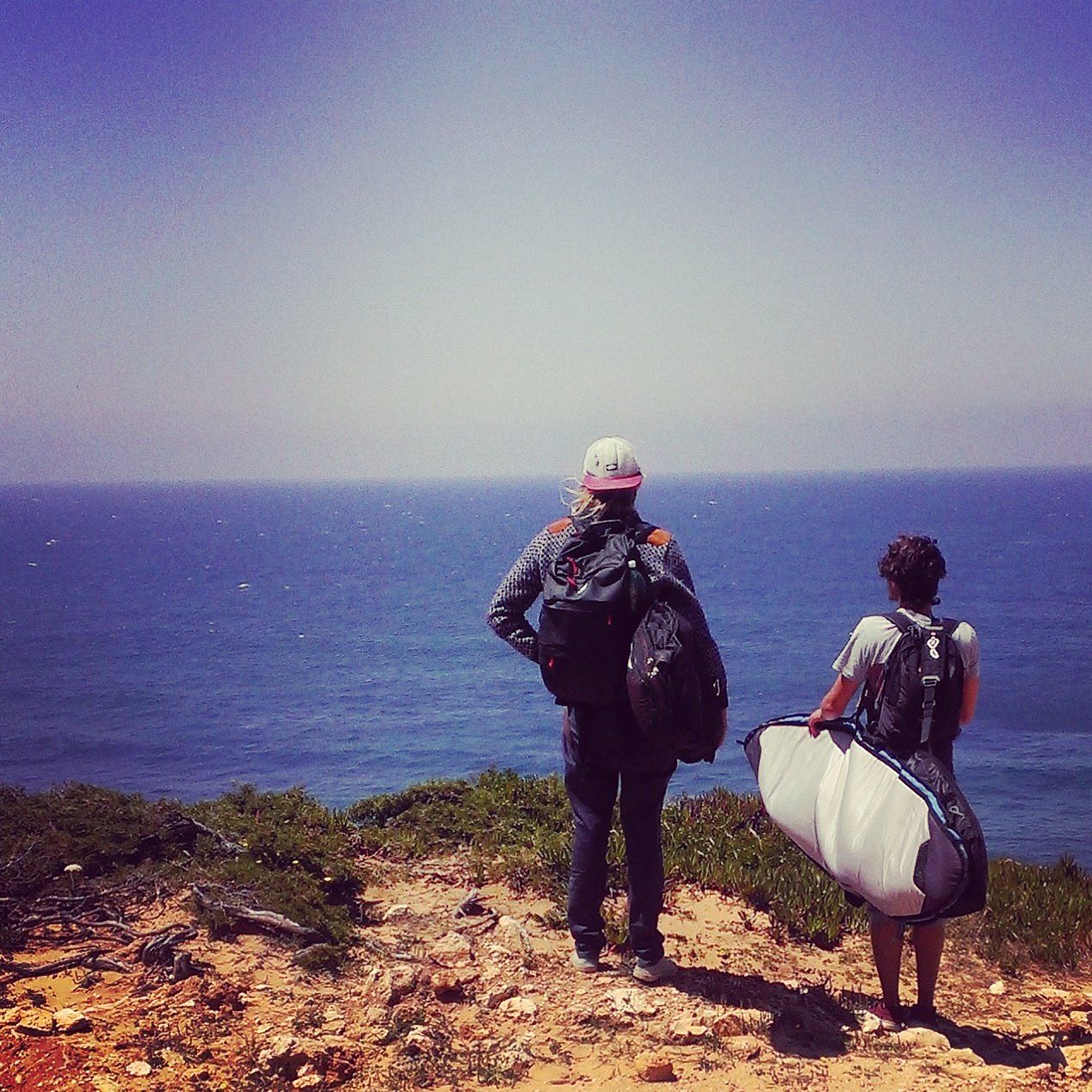 Two people standing on a hill overlooking the ocean