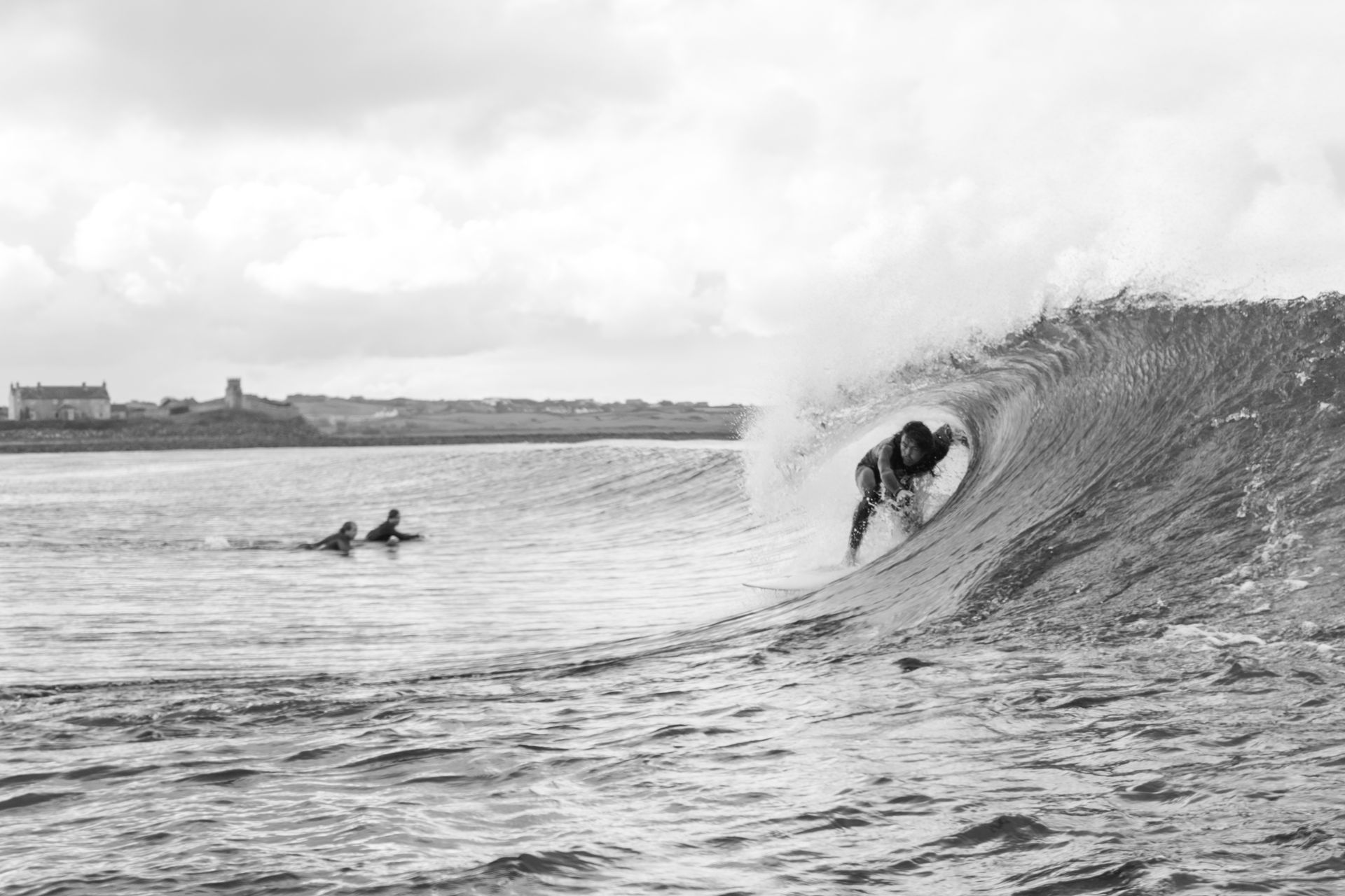 A black and white photo of a surfer riding a wave in the ocean.