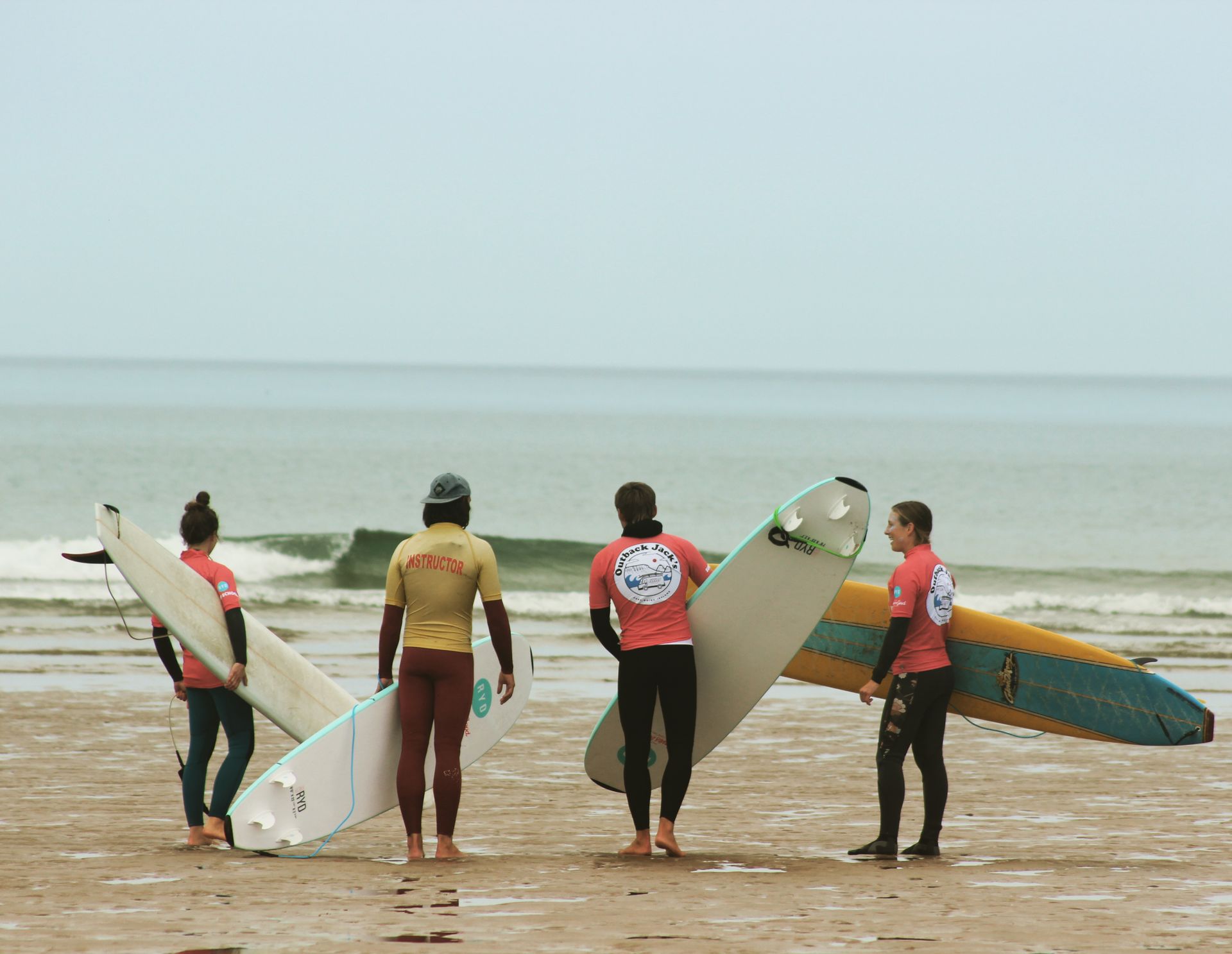 A group of surfers are standing on a beach holding surfboards.