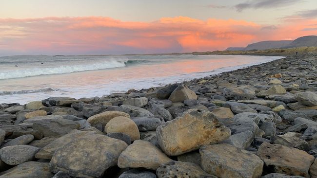 A rocky beach with a sunset in the background.