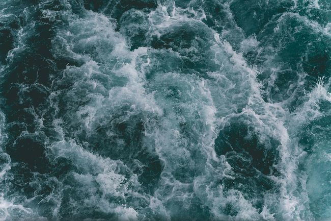 A close up of a body of water with waves and foam coming out of it.