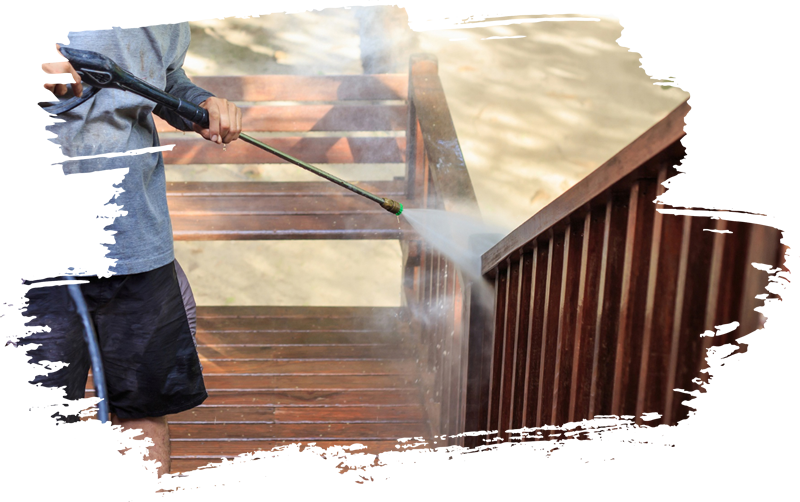 A person is using a high pressure washer to clean a wooden deck.