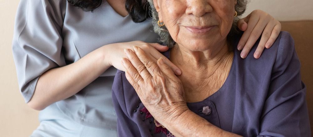 Woman resting her hand on another person’s arm in a supportive, close-up indoor scene