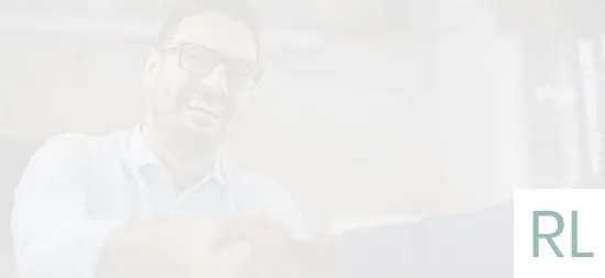 A man wearing glasses is smiling while looking at a tablet.