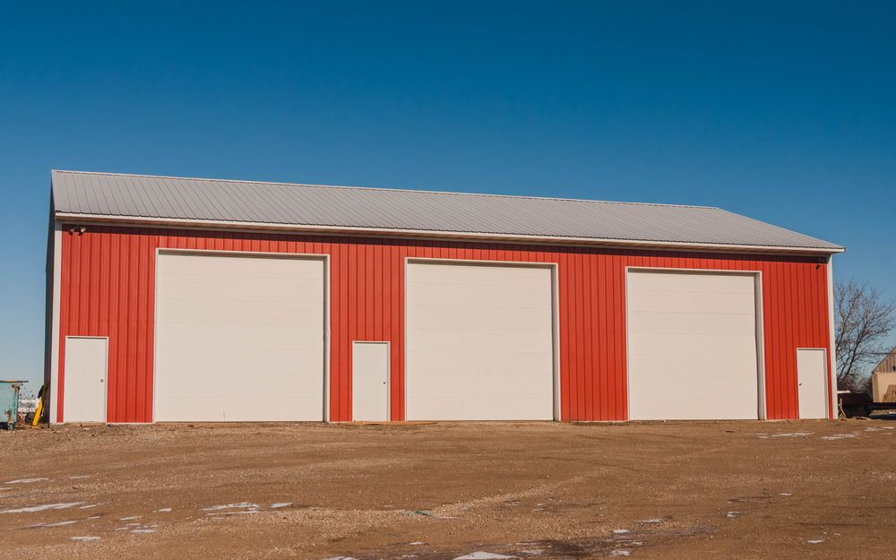 A Red Barn With White Doors is Sitting in the Middle of a Dirt Field — Accurate Fitout Solutions In Wetherill Park, NSW