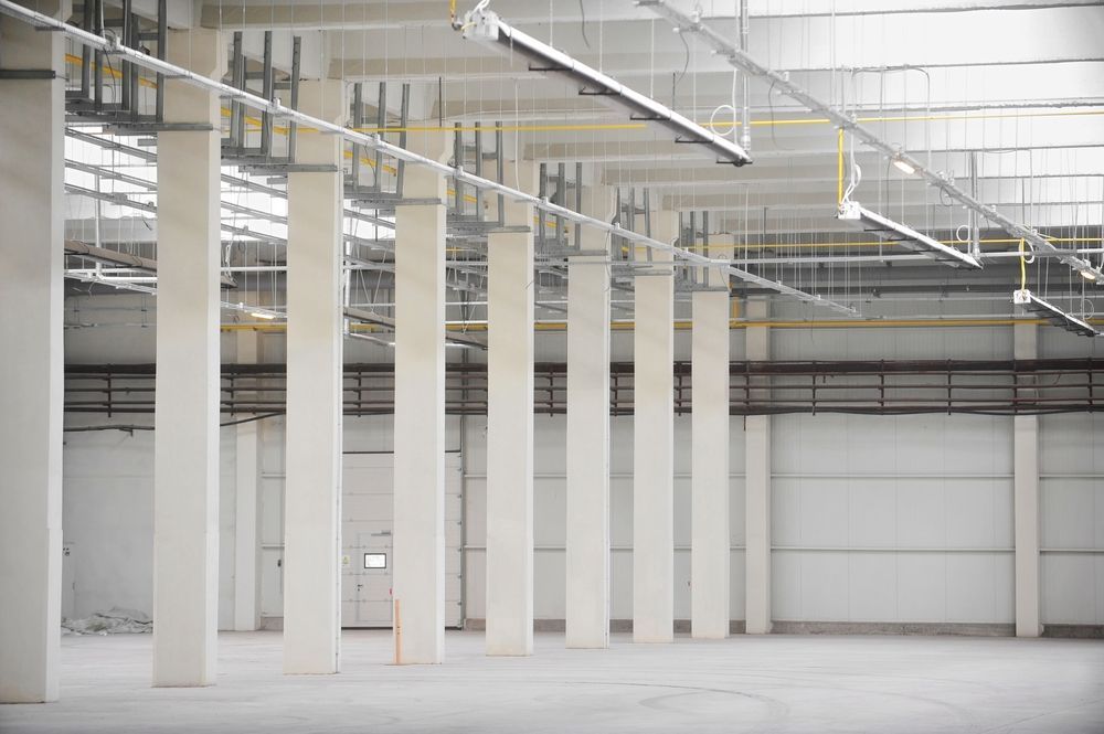 An Empty Warehouse With Columns and Pipes Hanging From the Ceiling — Accurate Fitout Solutions In Parramatta, NSW